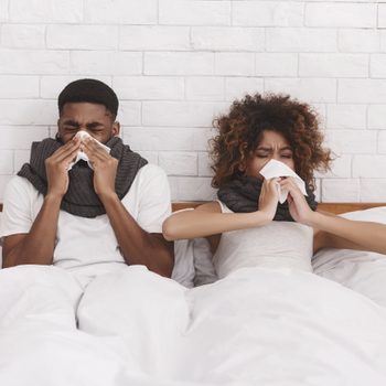 African American couple blowing nose tissue sick