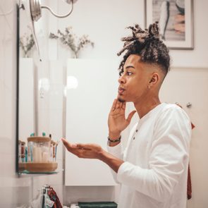 young man in bathroom washing his face