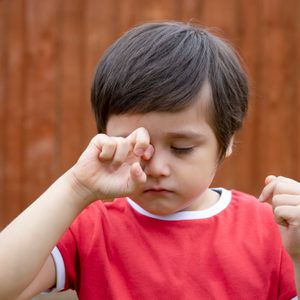 young boy rubbing his eye