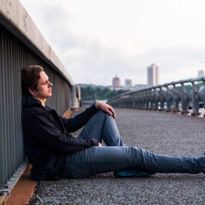 sad young man is sitting near fencing