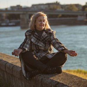 Senior woman enjoys meditating by the river.Toned image.