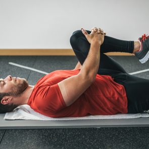 healthy man stretching leg before gym workout. Fitness strong male athlete. Male young fit exercising.