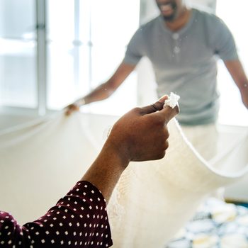 Black couple changing bed sheet together