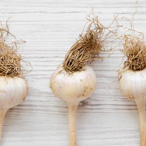 Garlic bulbs on white wooden table, overhead view. Copy space.