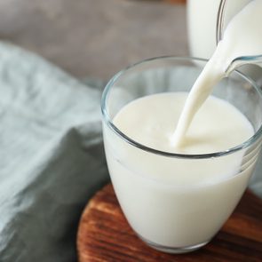 Pouring of milk into glass on table