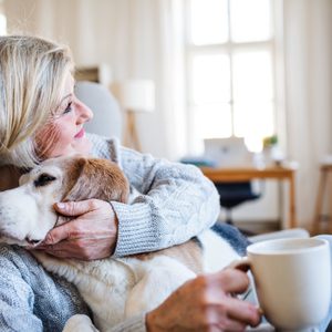 An active senior woman with a dog at home, resting.