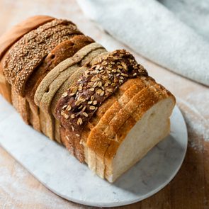 Sliced loaf made up of variety of white and wholemeal slices on cutting board, high angle view