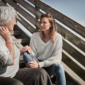 Senior woman talking with adult daughter on footbridge at the beach