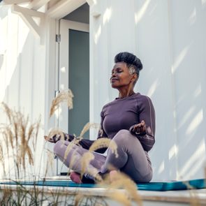 mature woman meditating in backyard