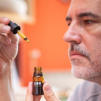 Mature Man Using CBD Oil at Home - Stock Photo