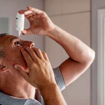 Mature Man Putting Eye Drops In Eyes