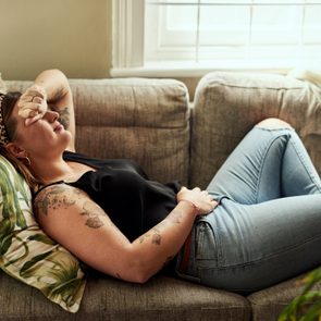 Shot of a young woman suffering from stomach cramps on the sofa at home