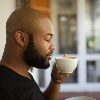 Millennial man smelling coffee in a cup