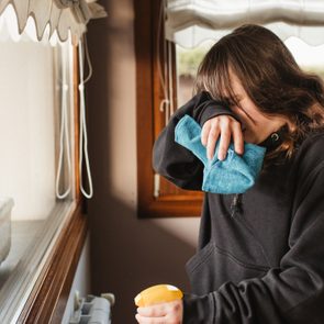 young woman cleaning a house and suffering from spring allergy headache