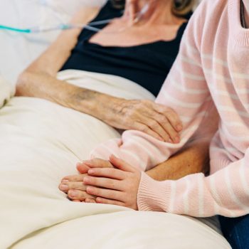 woman holding her mothers hands in hospice care