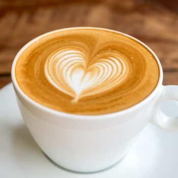 Close up white coffee cup with heart shape latte art