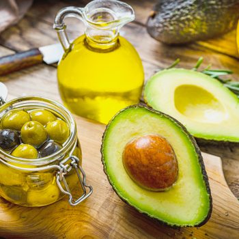 avocado, olives and olive oil on a wooden kitchen surface