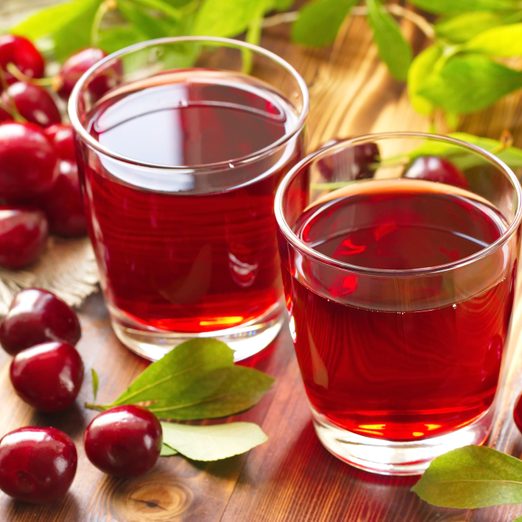 Cherry juice with fresh berries and leaves on a wooden background